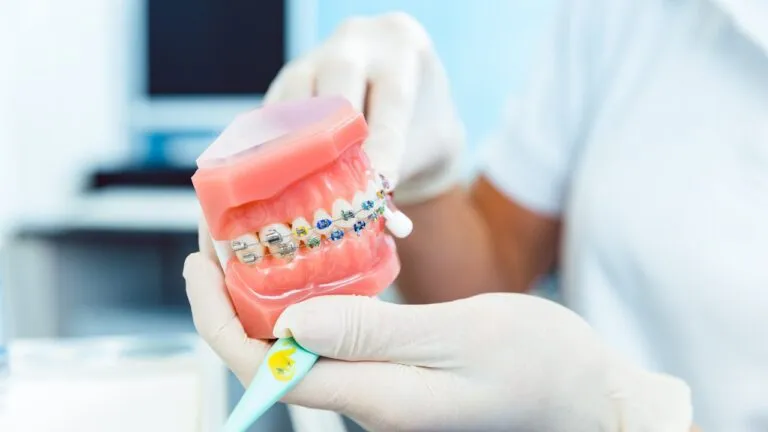 Orthodontist examining teeth with braces and power chains, considering factors like malocclusion severity, treatment stage, and patient comfort for optimal tooth alignment.